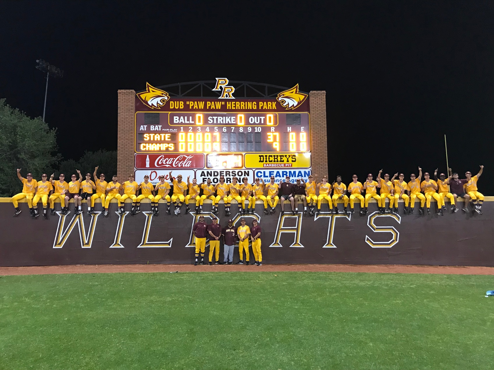 Pearl River players and coaches pose in front of the scoreboard at Dub Herring Park Sunday night to celebrate the Wildcats&rsquo; winning the MACJC state championship.